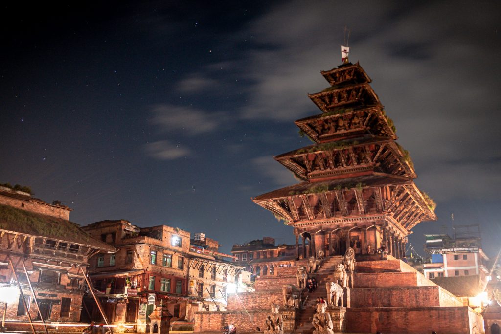 Nyatapola Temple in Bhaktapur, illuminated at night under a starry sky.