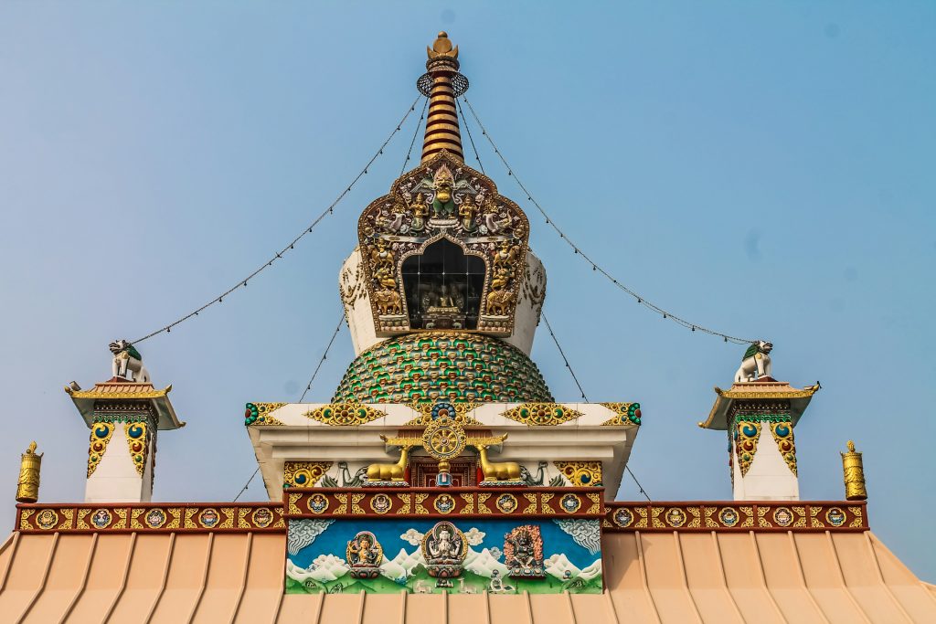 Ornate Buddhist stupa in Nepal with a gilded spire, detailed relief carvings, and colorful painted panels.